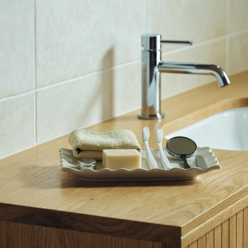 Personal care tools arranged in a ceramic tray on a bathroom counter
