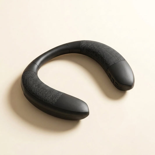 Black TV neckband speaker resting on a cream studio background, showing the U-shaped wearable design with fabric speaker grilles and side buttons