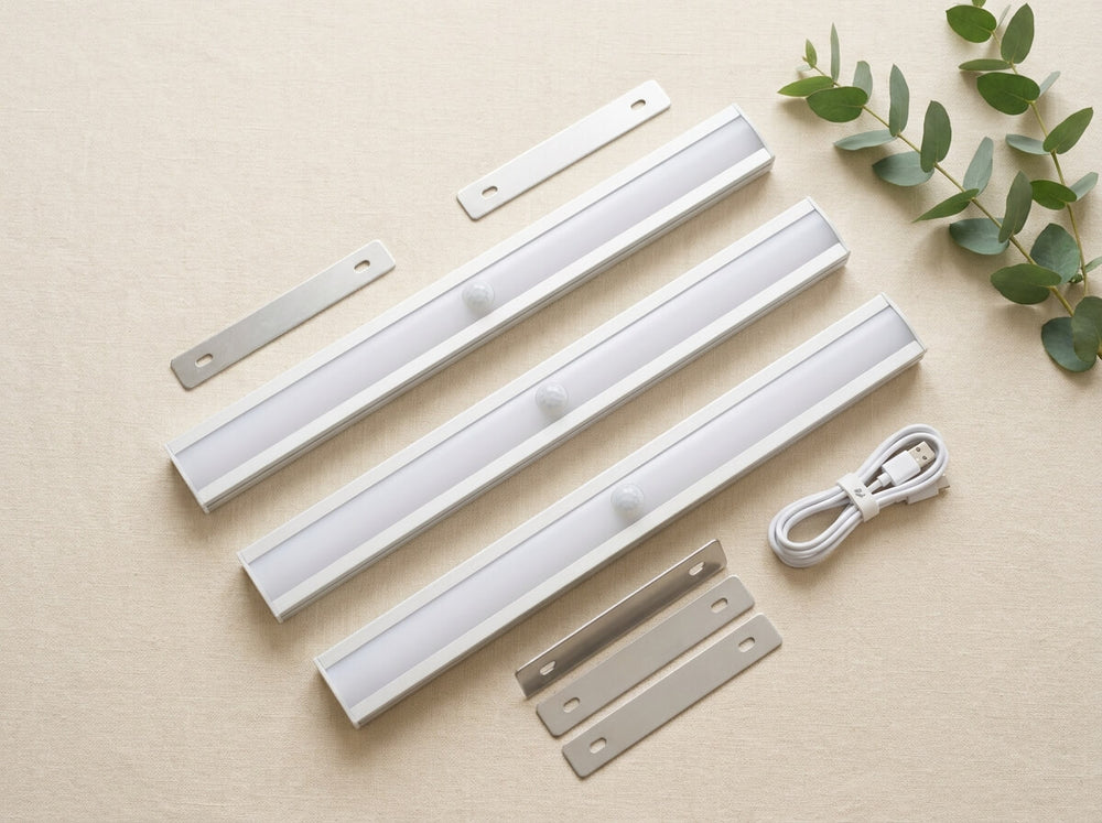 Three silver light bars, three metal mounting plates and a white USB-C cable laid on linen: the Triple set.